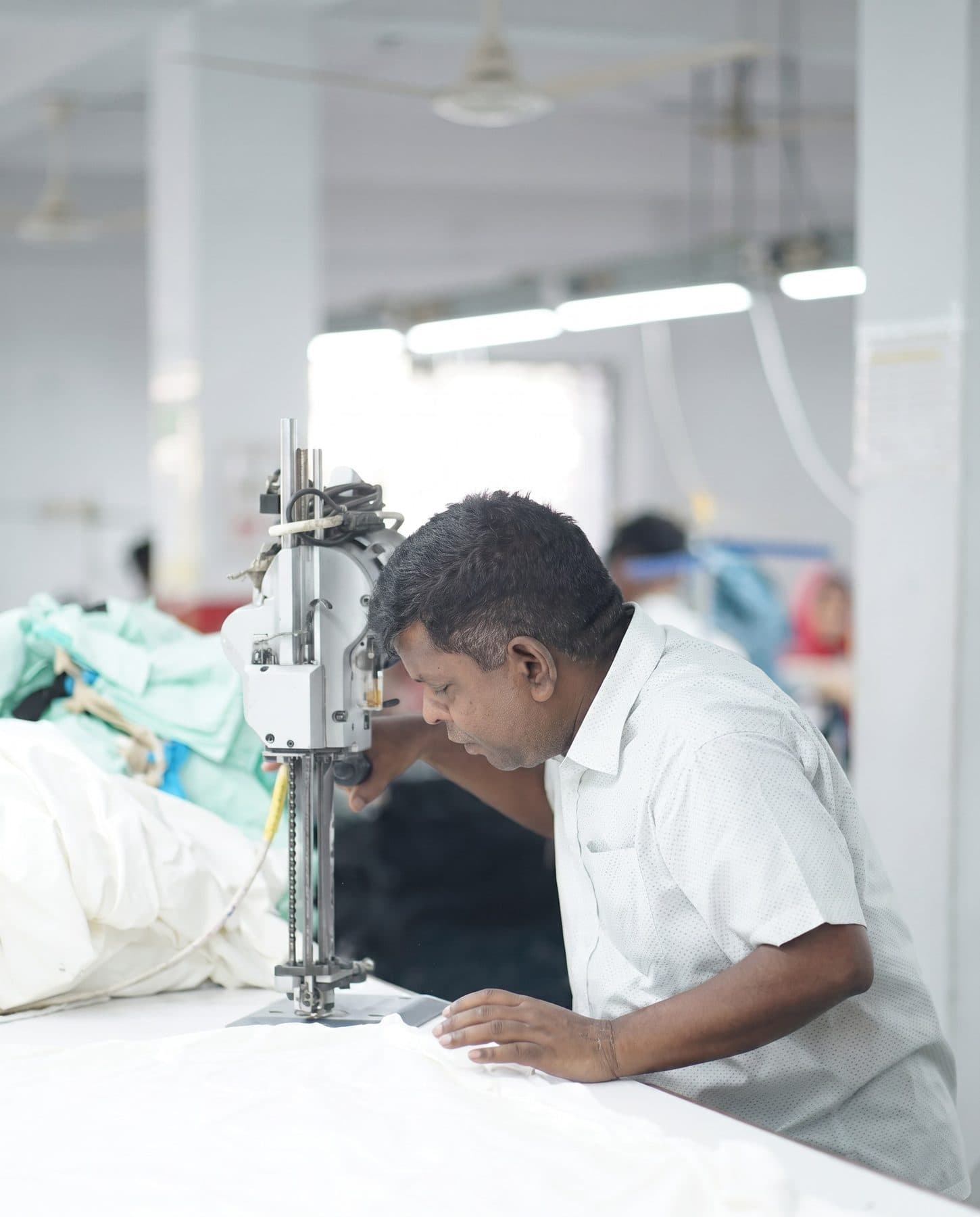 Cutter guiding a straight-knife cutting machine through layered white fabric