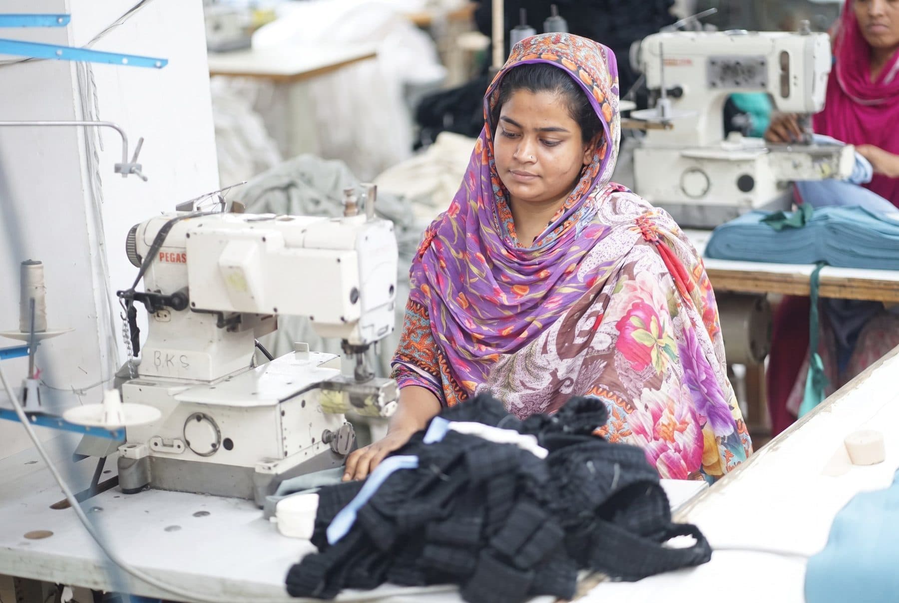 Sewing operator finishing black garments on an overlock machine