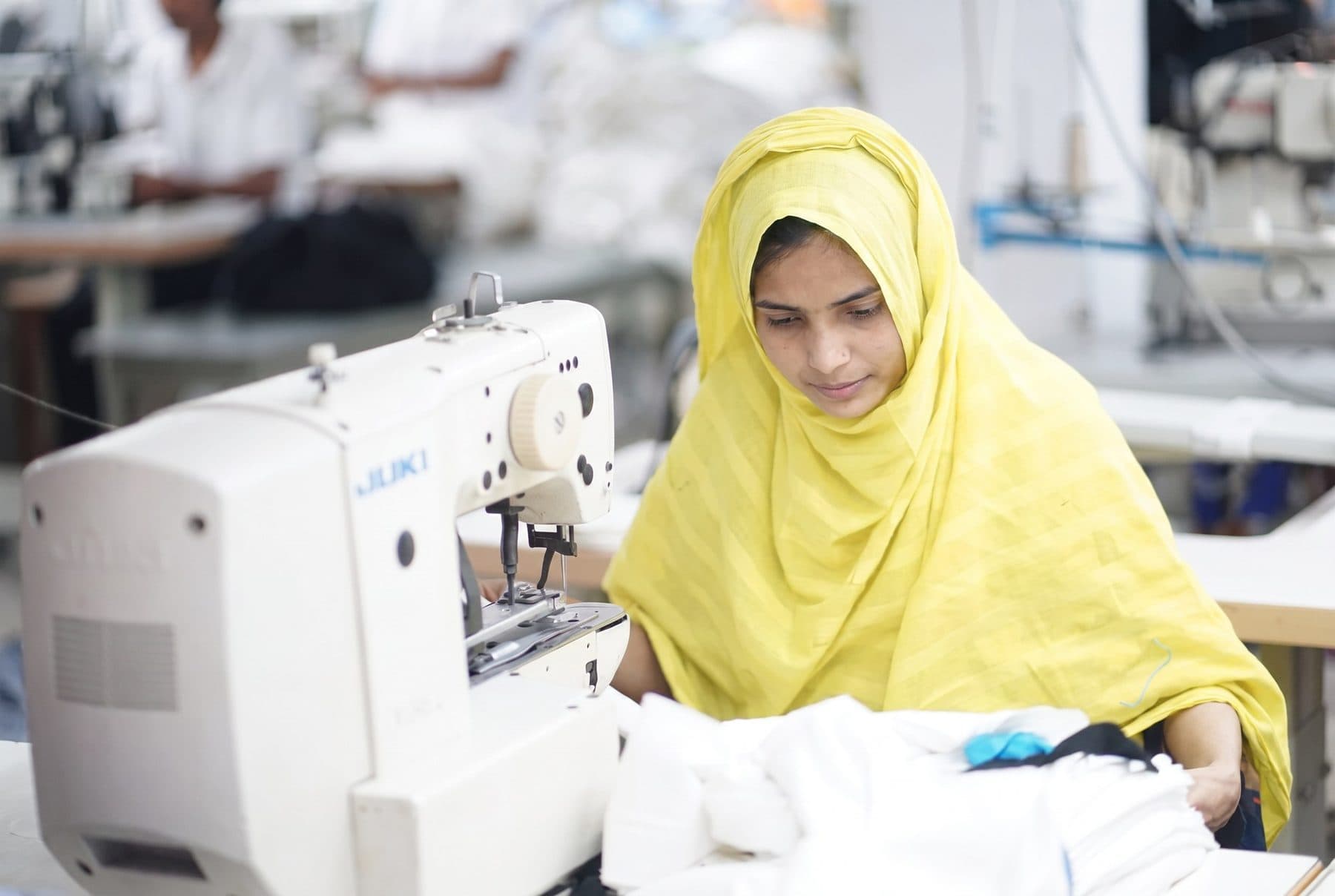 Sewing operator in a yellow hijab working at a Juki machine